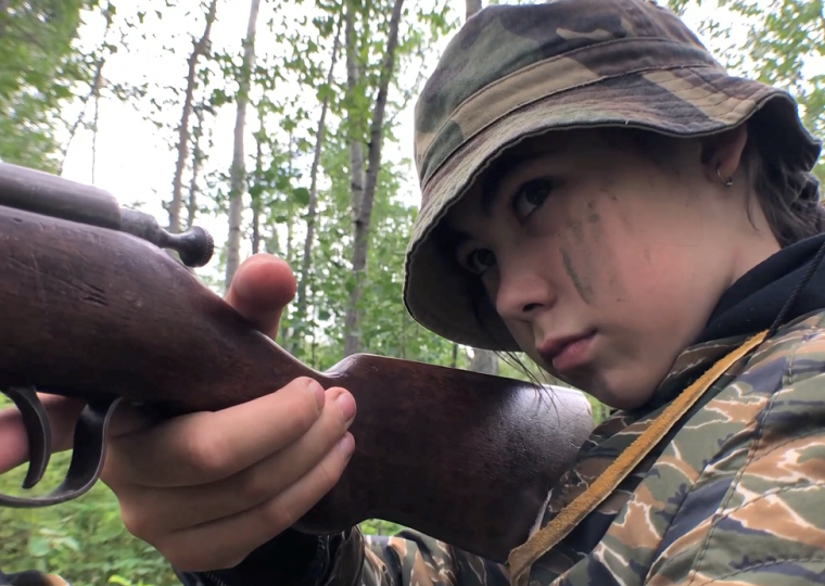 Child holding rifle in forest